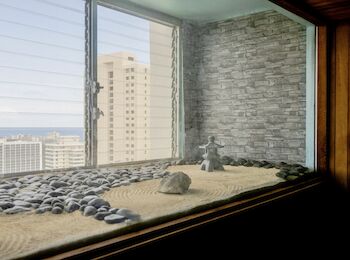 The image shows a Zen sand garden with rocks near a window overlooking a cityscape with high-rise buildings and a view of the ocean ending the sentence.